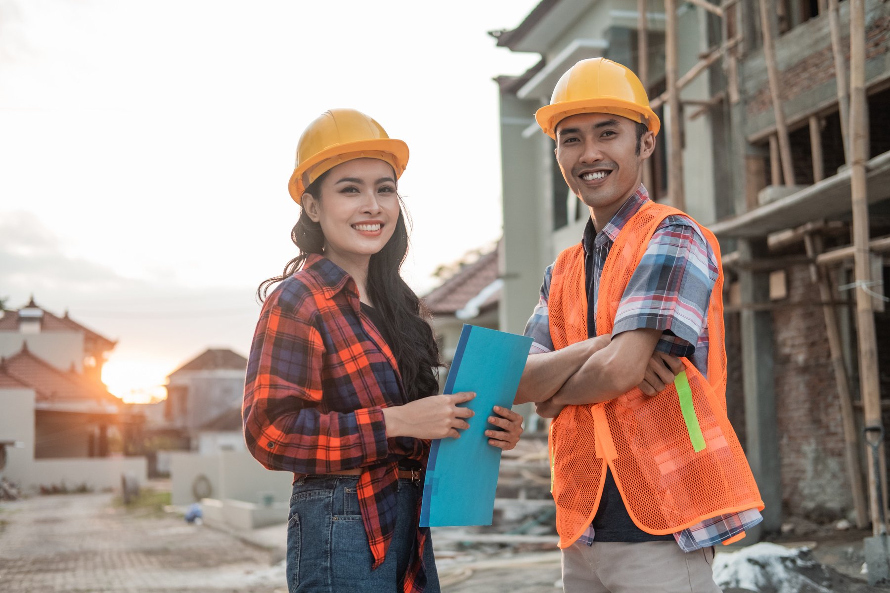 Two Asian Contractors Stood Wearing Safety Helmets and Vests